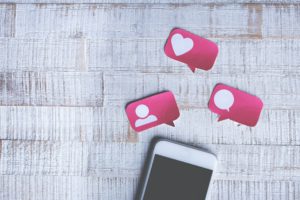 white cell phone with a heart icon and comment icon