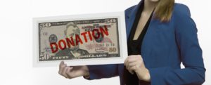 woman holding a large $50 bill with the word donation on it in red