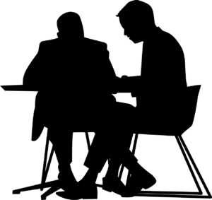 silhouette of two people sitting down at a table talking closely 