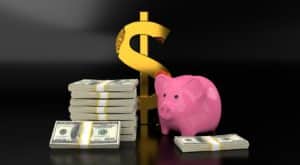 pink piggy bank next toa  gold dollar sign and stacks of cash