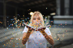 woman blowing confetti from a book