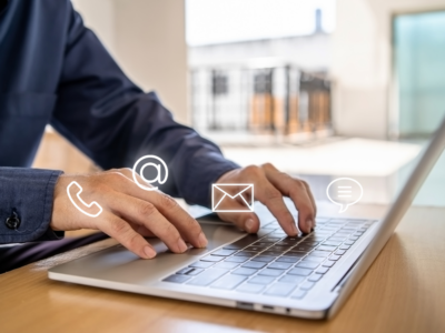 person typing on a laptop with icons for email, phone, and chat, illustrating the importance of multi-channel communication in engaging and converting business insurance leads.
