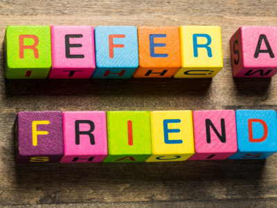 Brightly colored building blocks spelling "Refer a Friend," symbolizing a referral program for generating new insurance leads.