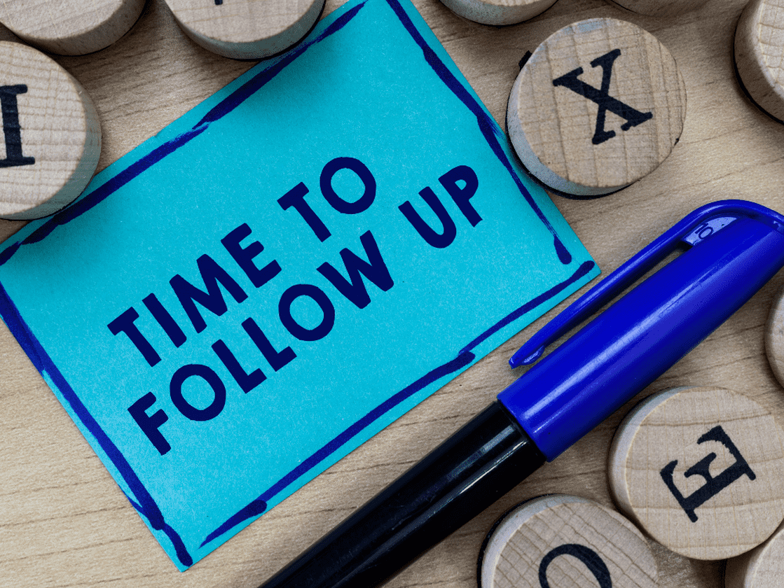 A blue sticky note with the words "Time to Follow Up" next to a pen and wooden letter blocks, emphasizing the importance of timely client follow-ups in insurance sales.